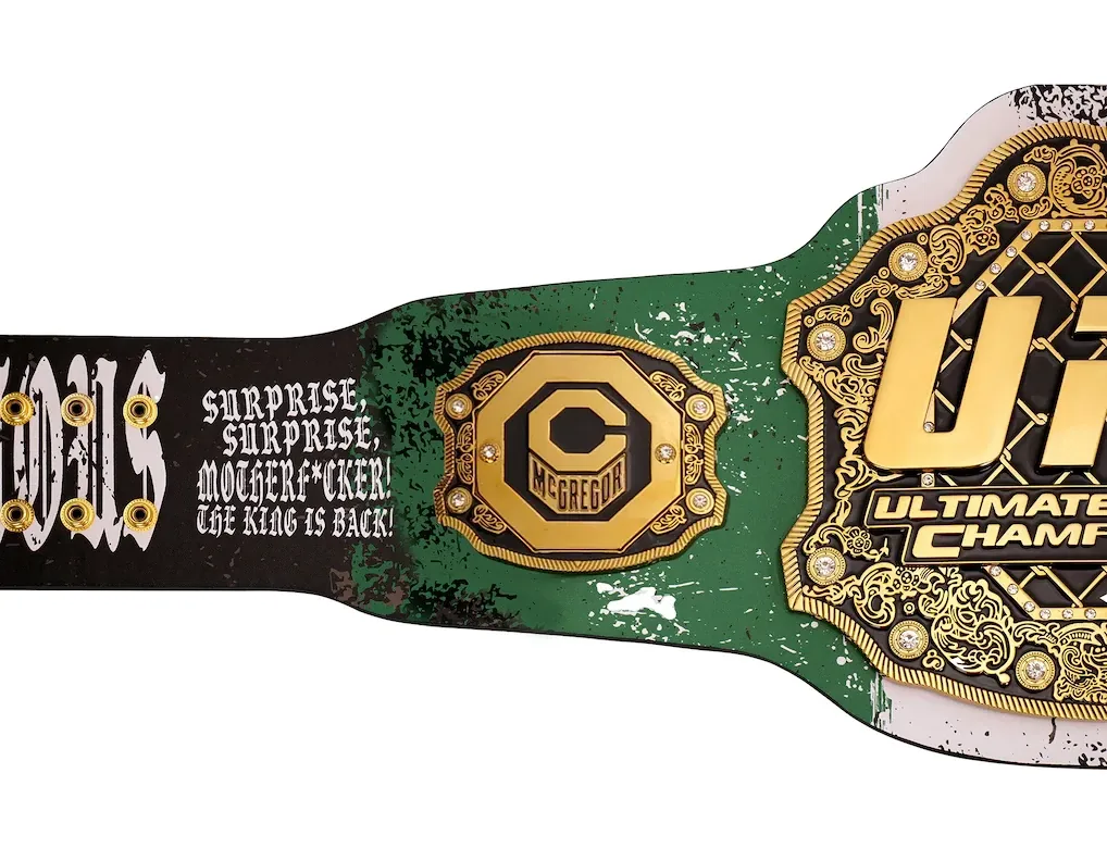 Close-up of the left strap on the Conor McGregor UFC 329 Classic Signature Replica Belt featuring signature artwork and quote.